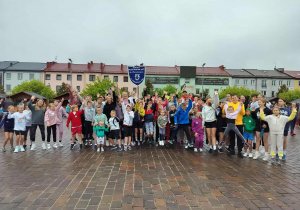 Grupa uczniów i rodziców pozuje do zdjęcia, w tle budynki