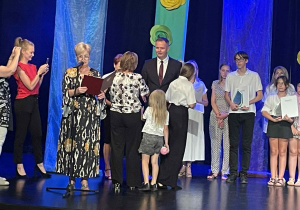 Dziewczynka odbiera nagrodę z rąk wysokiego mężczyzny