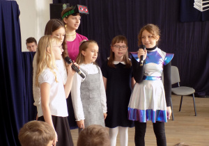 Dziewczynki w różnorodnych przebraniach, trzymają mikrofon