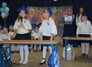 Dwie dziewczynki w galowych strojach, przy mikrofonie