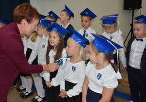 Kobieta przykłada duży ołówek do ramienia dziecka