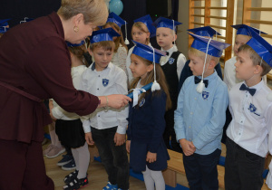 Kobieta przykłada duży ołówek do ramienia dziecka