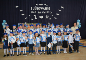 Zdjęcie grupowe dzieci ubranych w galowe stroje na tle granatowego tła