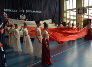 Uczennice trzymają w dłoniach biało- czerwone tkaniny ułożone w barwy narodowe