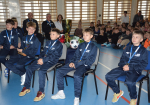 Chłopcy w sportowych strojach, w tle uczniowie