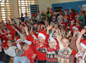 Dzieci w mikołajowych czapkach machają rękami