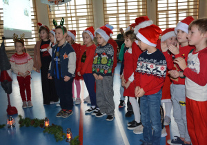 Dzieci w świątecznych przebraniach, śpiewają piosenkę dla Mikołaja