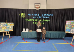 Dziewczynki stoją na tle prac konkursowych