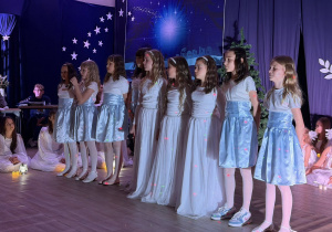 Uczennice w niebieskich spódniczkach śpiewają piosenkę