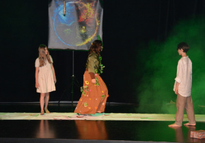 Dziewczynka i chłobiec, pomiędzy nimi dziewczynka przebrana za Ziemię