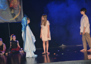 Dziewczynka i chłopiec, obok dziewczyna w błękitnej sukni