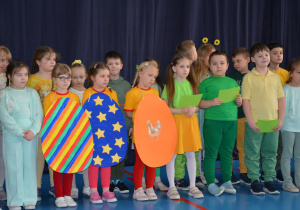 Trzy dziewczynki trzymają papierowe, kolorowe pisanki