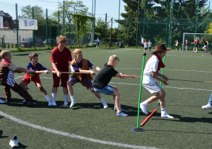 Dzieci przeciągają linę, na boisku sportowym